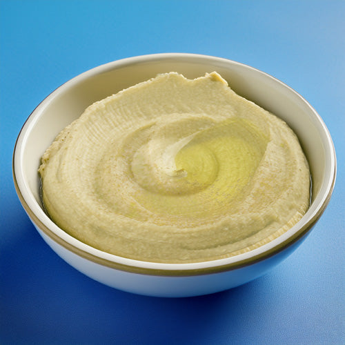 A photo of hummus in a white bowl on a blue background. 